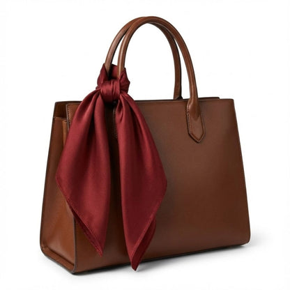 Foulard en satin rouge noué sur un sac à main marron, ajoutant une touche élégante et sophistiquée