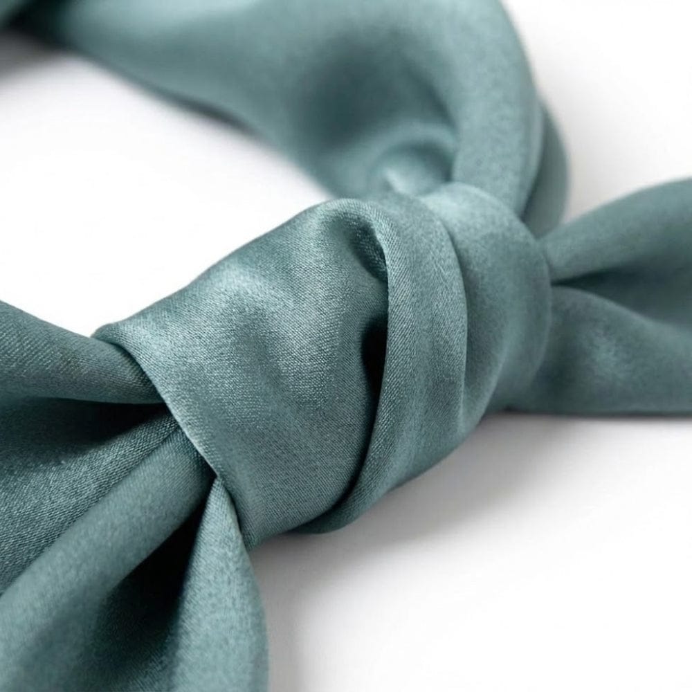 Foulard en soie vert d'eau, noué avec élégance, mettant en avant sa texture satinée et sa teinte pastel