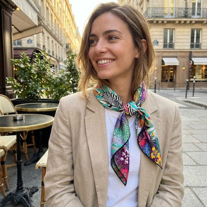 Foulard en soie coloré avec motifs floraux et zébrés noué autour du cou d'une femme élégante en extérieur