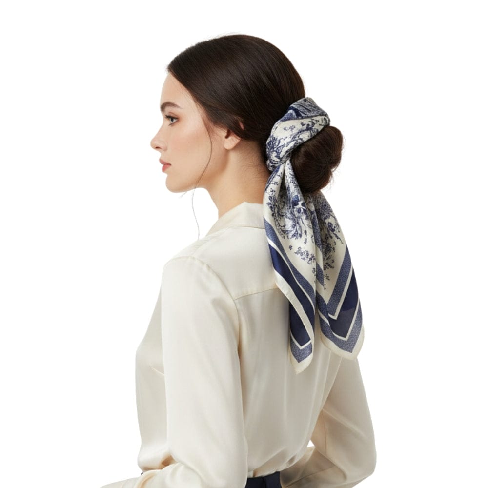 Foulard en soie bleu marine à motifs floraux, noué élégamment dans les cheveux d'une femme en chemise claire