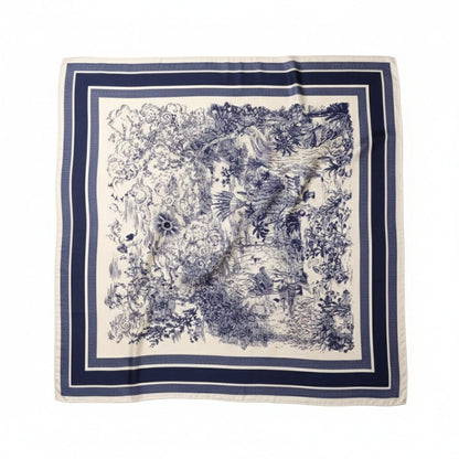 Foulard carré en soie avec motifs floraux bleus sur fond crème et bordure bleu marine, posé à plat
