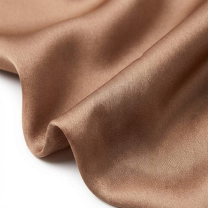 Foulard en soie de couleur marron, doux et brillant, drapé élégamment sur une surface blanche