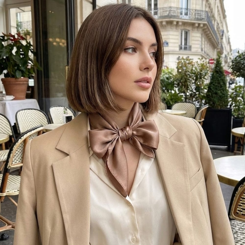 Foulard en satin noué de couleur brune porté autour du cou d'une femme, dans un café parisien élégant