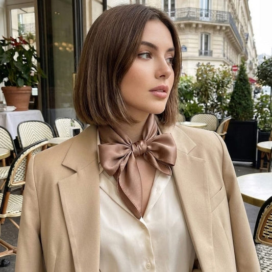 Foulard en satin noué de couleur brune porté autour du cou d'une femme, dans un café parisien élégant