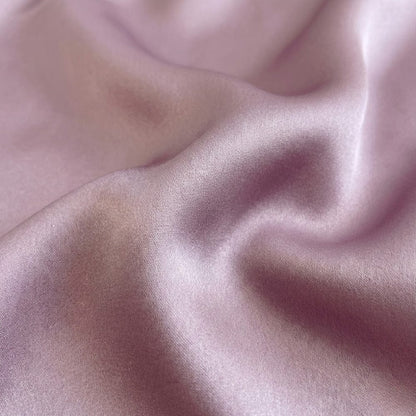 Foulard en soie parme délicat, avec une texture lisse et brillante, drapé élégamment sur une surface douce