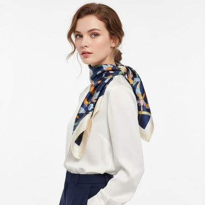 Foulard en satin bleu marine avec motifs floraux colorés, noué autour du cou d'une femme élégant