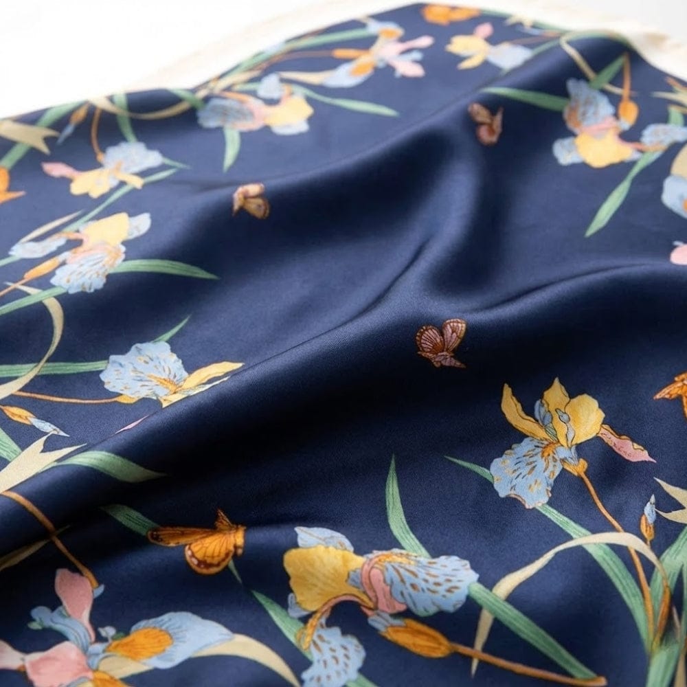 Foulard en satin bleu marine orné de motifs floraux colorés et délicats, idéal comme accessoire chic