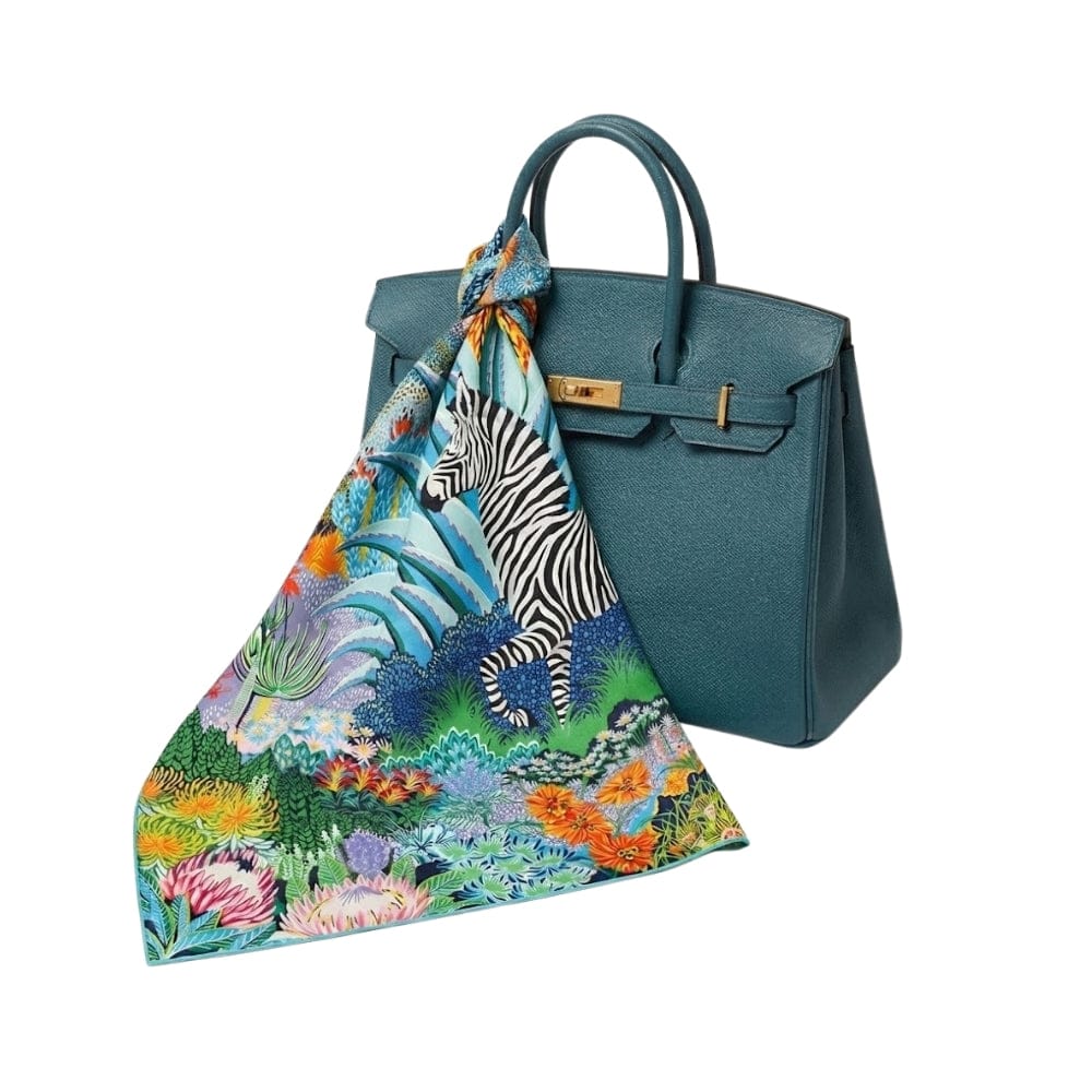 Foulard en soie aux motifs colorés de zèbre et de fleurs, noué sur un sac à main bleu