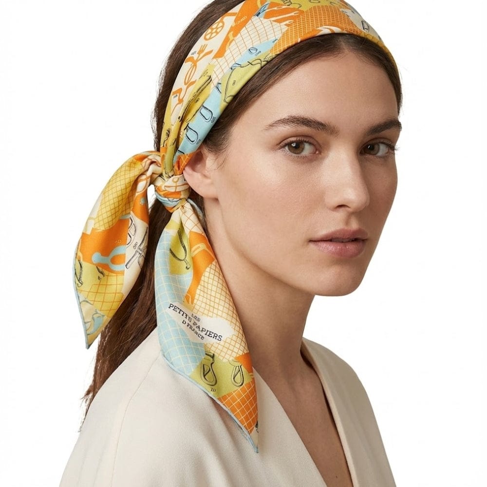 Foulard noué en satin aux motifs colorés orange et bleu, porté par une femme avec une tenue claire