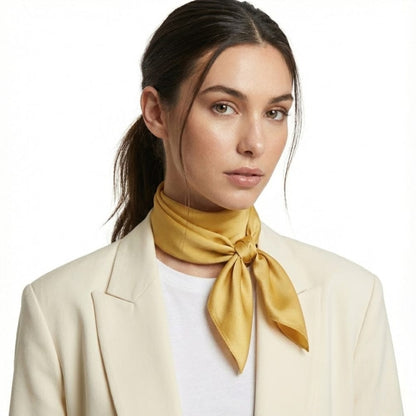 Foulard en soie jaune moutarde noué autour du cou d'une femme, avec un look sophistiqué