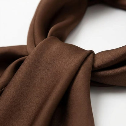 Foulard en satin marron aux teintes naturelles, noué avec élégance pour une allure sophistiquée