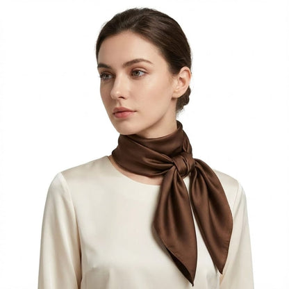 Foulard en satin marron noué autour du cou d'une femme, apportant une touche sophistiquée à une tenue élégante