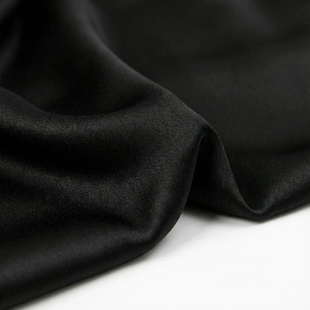 Foulard en satin noir, doux et élégant, drapé avec des plis subtils sur un fond clair