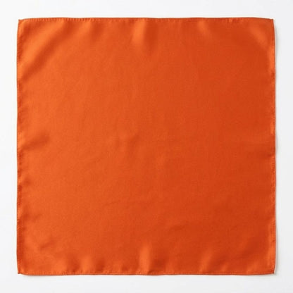 Foulard carré en soie orange, d'une texture lisse et brillante, posé sur un fond neutre