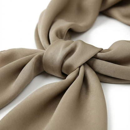 Foulard en satin doux de couleur beige noué, mettant en valeur sa texture lisse et élégante