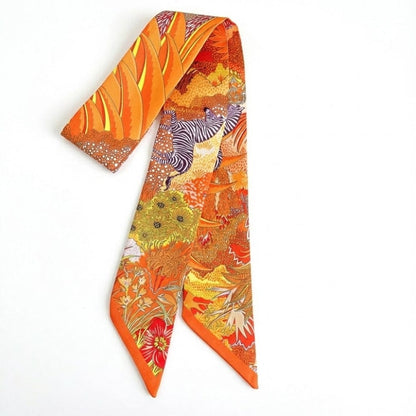 Foulard en satin aux motifs floraux colorés, dominé par des teintes orange et jaune, présenté sur fond blanc