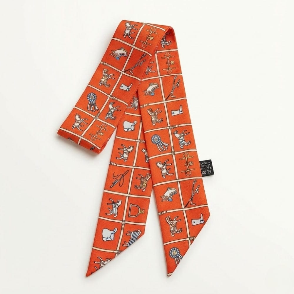 Foulard en satin orange avec motifs graphiques colorés, idéal pour accessoiriser un sac à main