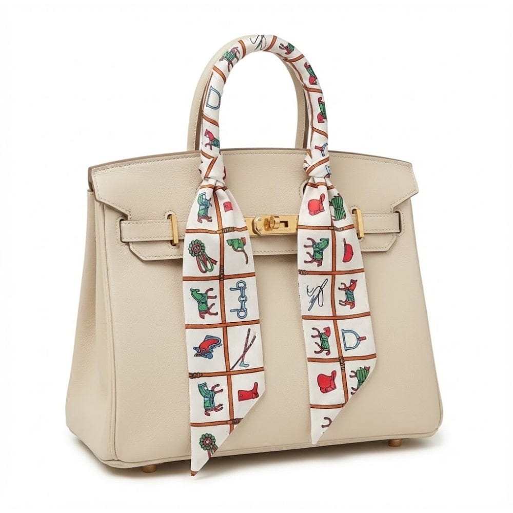 Foulard en soie noué sur un sac à main beige, avec motifs colorés de dessins ludiques et élégants