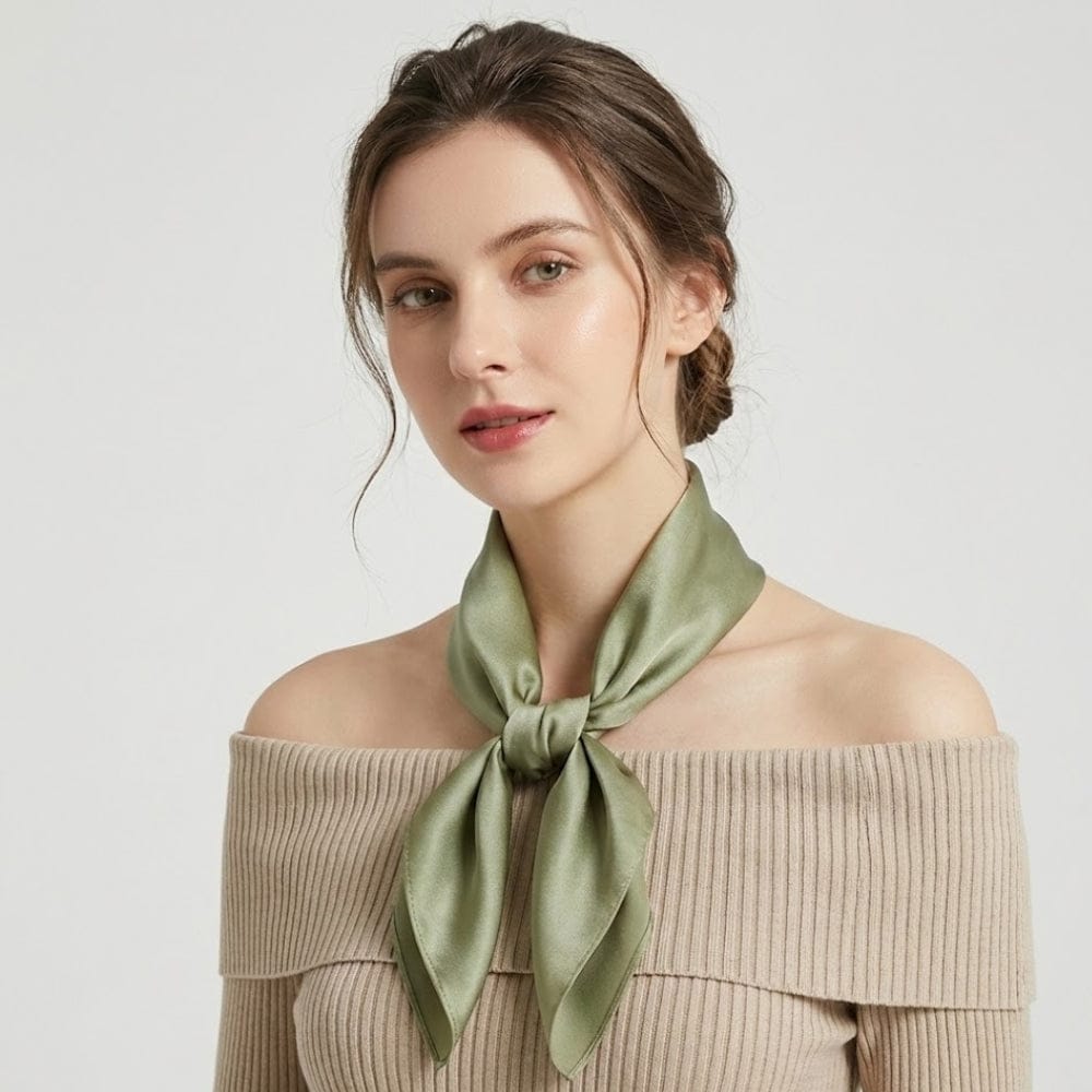 Foulard en soie vert noué autour du cou d'une femme, sur fond neutre, mettant en valeur sa douceur et son