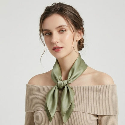 Foulard en soie vert noué autour du cou d'une femme, sur fond neutre, mettant en valeur sa douceur et son