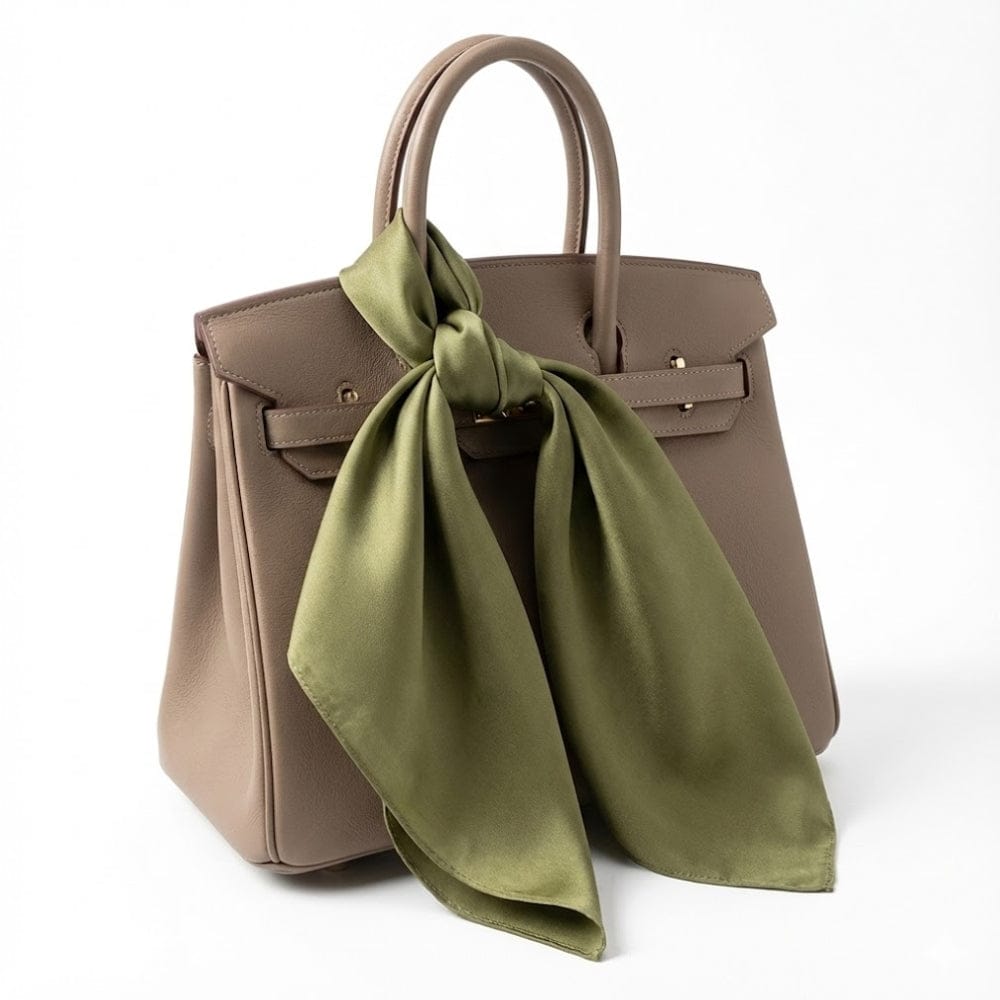 Foulard en soie vert noué sur une élégante sacoche beige, mettant en valeur sa douceur et sa brillance
