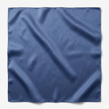 Foulard carré en soie bleu, brillant et lisse, posé sur une surface blanche, mettant en valeur sa texture raffinée