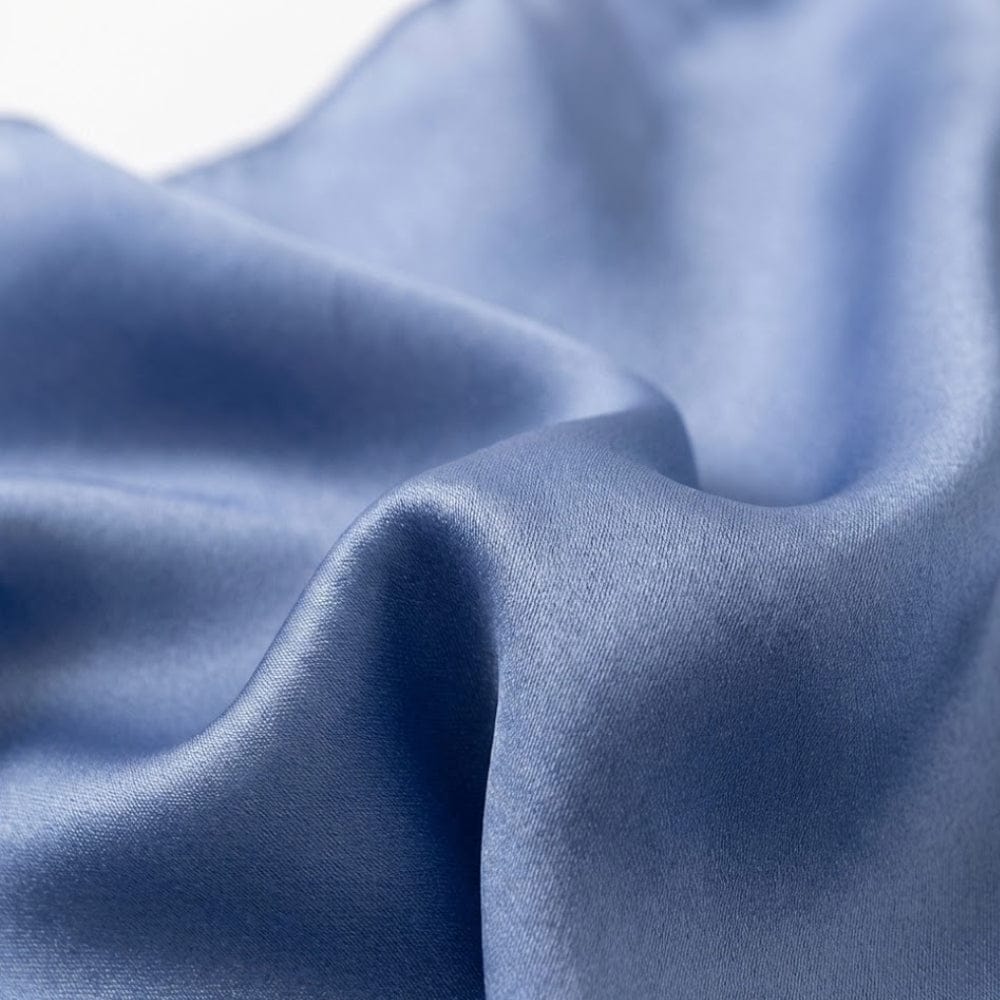 Foulard en soie bleu, au toucher doux et brillant, drapé élégamment sur un fond neutre